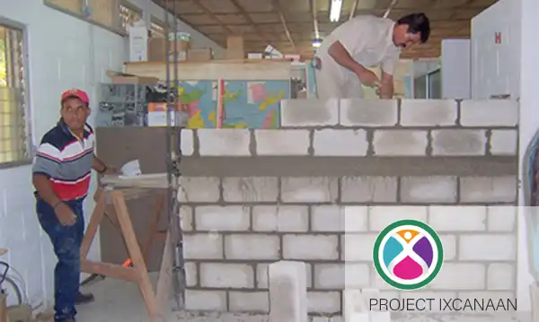 Two men constructing a block wall inside the Project Ixcanaan clinic in El-Ramate, Guatemala.